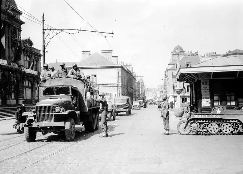 American troops advance through Cherbourg, France, in 1944. To the right: a captured Nazi Kettenkrad half-track, repurposed by U.S. forces
