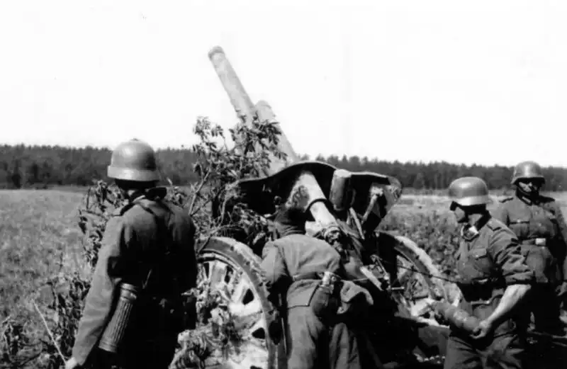 German 105mm leFH18 field howitzer crew preparing to fire from a concealed position during World War II.