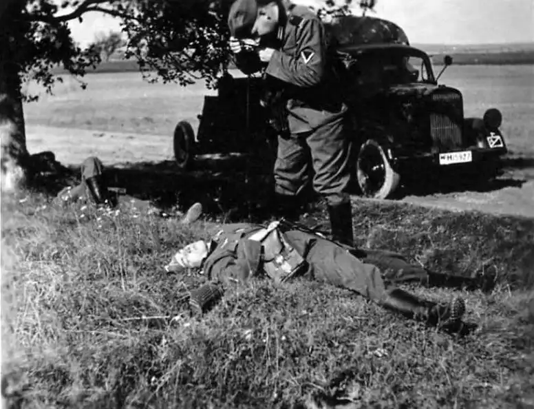 German Wehrmacht soldiers sleeping beneath a tree during the Battle of France while a comrade photographs them near an Opel Blitz truck towing a PaK 35/36 anti-tank gun, June 1940.