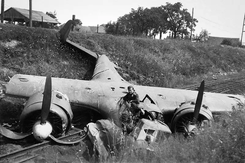 Black and white historical photo of a destroyed German Dornier Do 17Z twin-engine bomber lying across a railway track embankment in 1940.