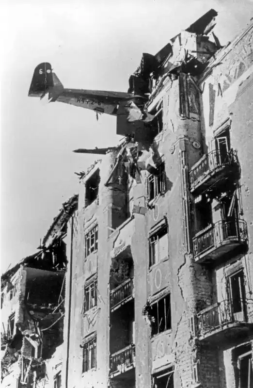 Wreckage of a German DFS 230 transport glider protruding from the upper floor of a damaged brick residential building in Budapest, photographed by Yevgeny Khaldei in 1945.