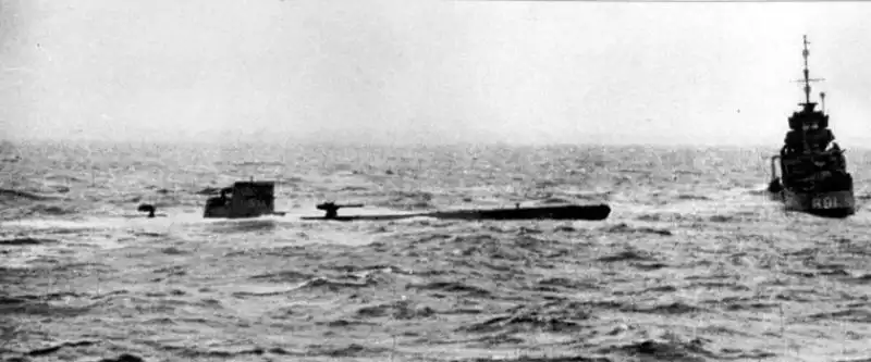British sailors board the damaged German submarine U-110 in the North Atlantic after forcing it to surface, leading to the capture of an Enigma machine and secret naval codebooks, May 1941.