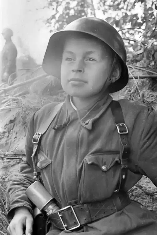 Black and white historical portrait by Evgeny Khaldei of young Soviet soldier Valdemar Pilain wearing an SSH-40 helmet and carrying an RGD-33 grenade in 1941.
