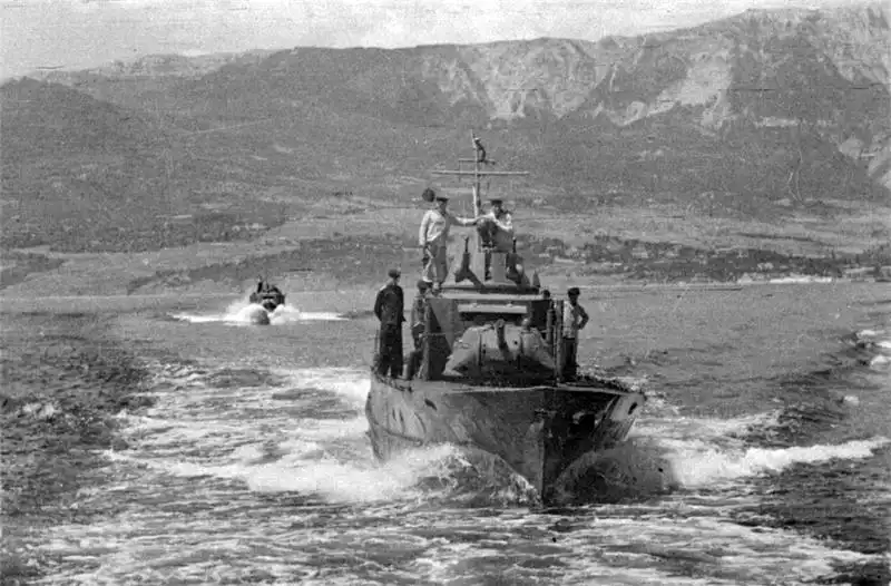 Black and white historical photograph by Evgeny Khaldei showing a Soviet Project 1125 armored gunboat with a T-34 tank turret cruising near Yalta in 1944.