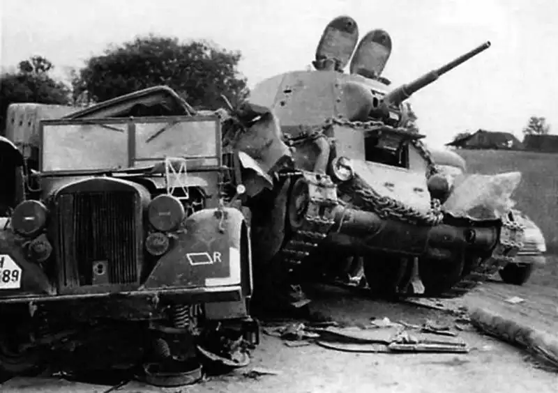 A Soviet BT-7 light tank with open turret hatches resting its tracks on the crushed hood of a German Wehrmacht staff car in Lithuania, June 1941.