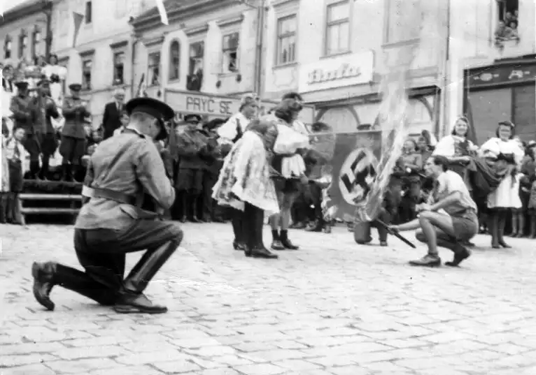 Civilians in traditional Czech clothing burn a Nazi flag in liberated Czechoslovakia while Red Army soldiers watch in summer 1945