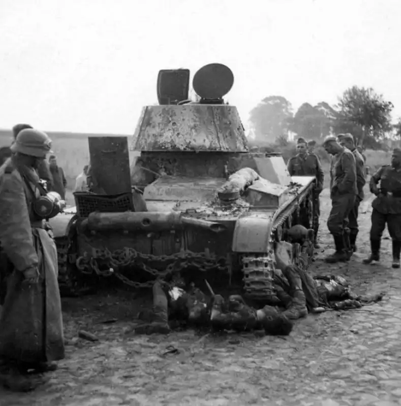 Knocked-out Soviet T-26 light tank Model 1939 with fallen crew members on cobblestone road 1941.