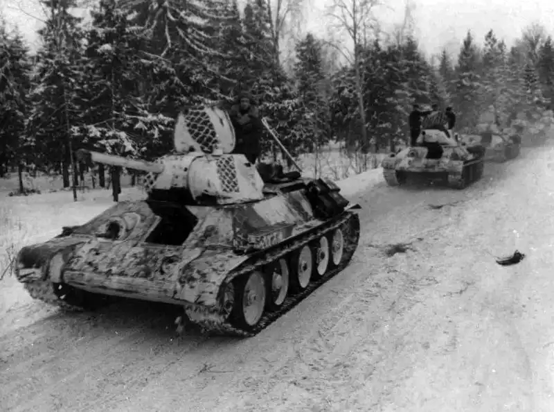 Column of Soviet T-34-76 tanks from the 1st Guards Tank Brigade wearing rare tire-track winter camouflage during the winter campaign of 1942.