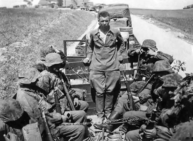Captured Soviet Red Army officer sitting in the back of a German truck surrounded by Waffen-SS soldiers during the summer campaign of 1942.