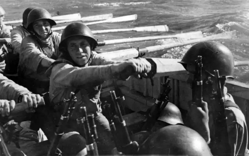 Soviet Baltic Fleet naval infantrymen rowing a wooden boat while armed with Mosin-Nagant rifles in 1943.