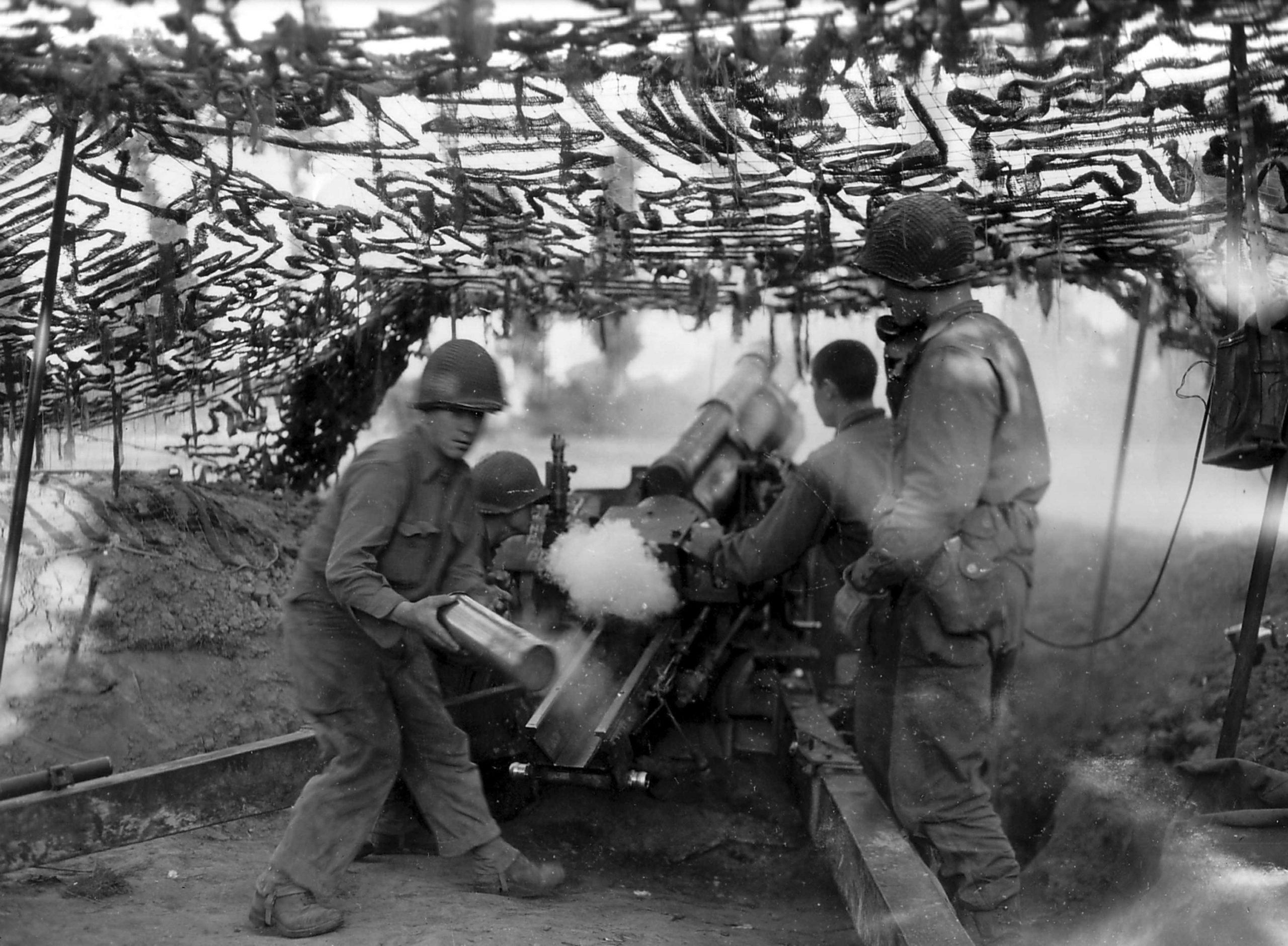 American gunners fire from a 105-mm howitzer